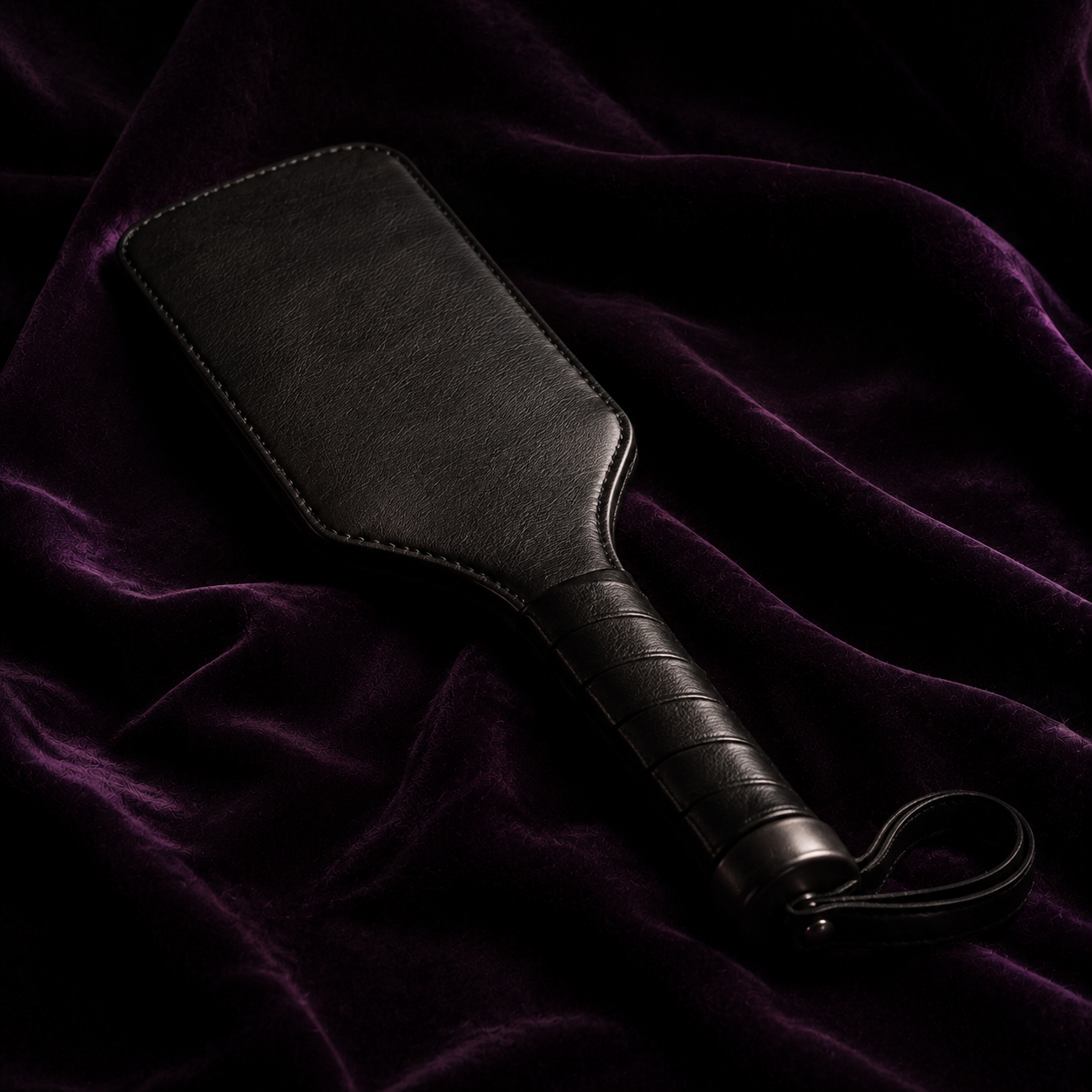 Paddle en cuir noir sur velours aubergine